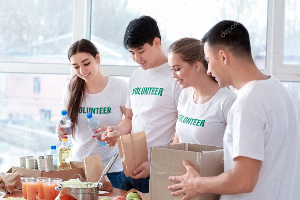 Young volunteers with food for poor people indoors