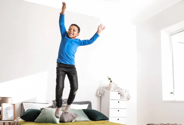 Счастливый афроамериканец, прыгающий на кровати дома — стоковое фото