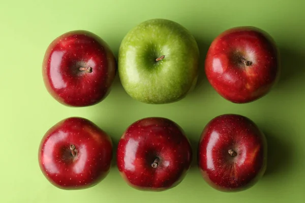 Green apple among red ones on color background. Concept of uniqueness — Stock Photo, Image