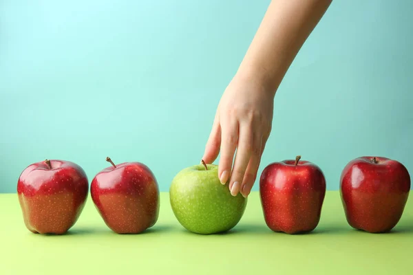 Mano femenina con sabrosas manzanas sobre fondo de color. Concepto de singularidad —  Fotos de Stock