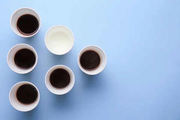 Cups with water and coffee on color background. Concept of uniqueness