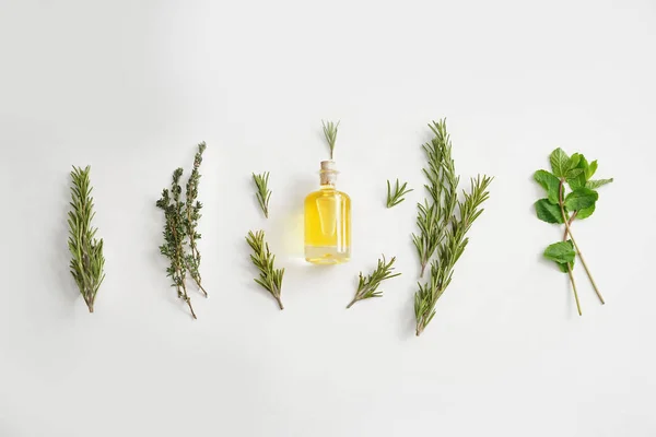 Botella de aceite con diferentes hierbas sobre fondo blanco —  Fotos de Stock