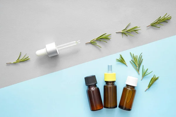 Bottles of rosemary oil on color background — Stock Photo, Image