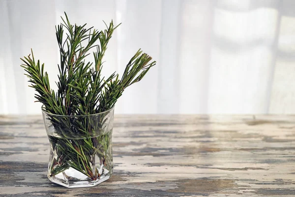 Romarin frais en verre avec de l'eau sur une table en bois — Photo