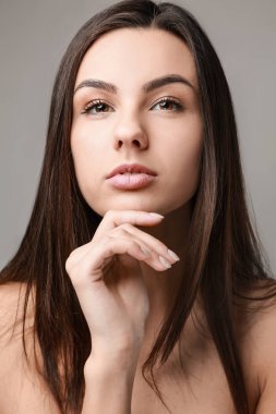 Gri arka plan üzerinde sağlıklı cilt ile güzel bir kadın portresi