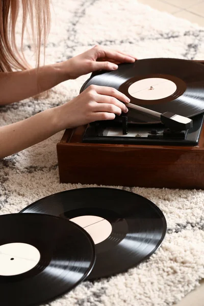 Jonge vrouw met oude platenspeler en vinyl schijven thuis — Stockfoto