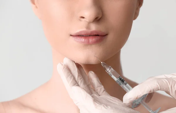 Young woman receiving injection in face on light background, closeup — Stock Photo, Image