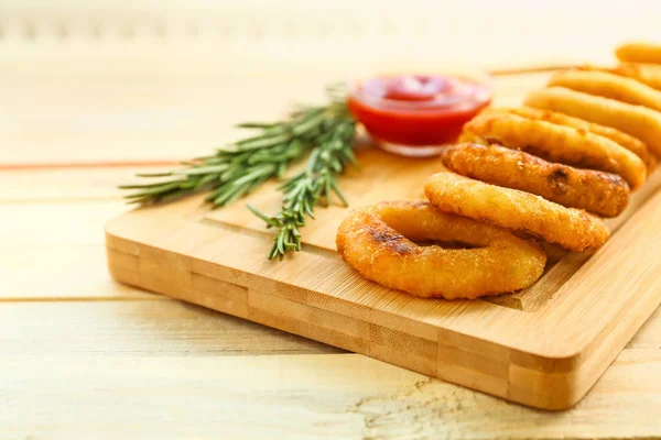 Styrelse med välsmakande lökringar och tomatsås på träbord — Stockfoto