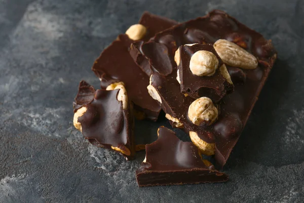 Kusů chutných tmavé čokolády s ořechy na pozadí grunge — Stock fotografie