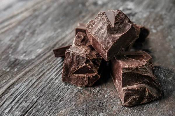 Κομμάτια από νόστιμα σοκολάτα σε φόντο ξύλινη — Φωτογραφία Αρχείου