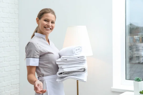 Beautiful female housekeeper with clean towels in room — Stock Photo, Image