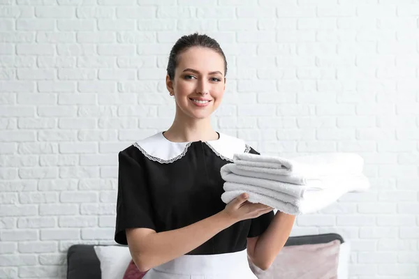 Beautiful female housekeeper with clean towels in room — Stock Photo, Image