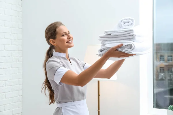 Beautiful female housekeeper with clean towels in room — Stock Photo, Image