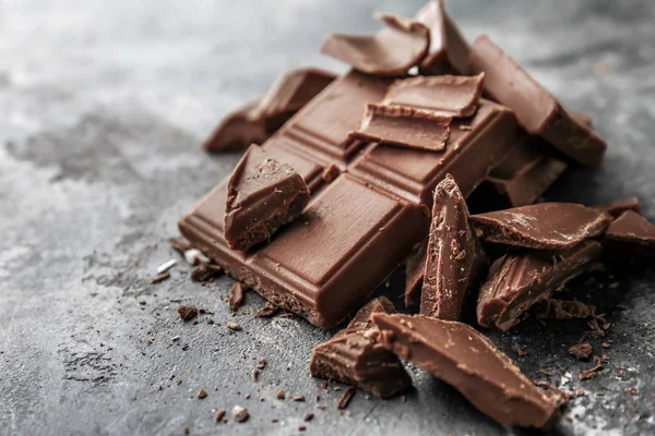 Pieces of tasty milk chocolate on grunge background — Stock Photo, Image