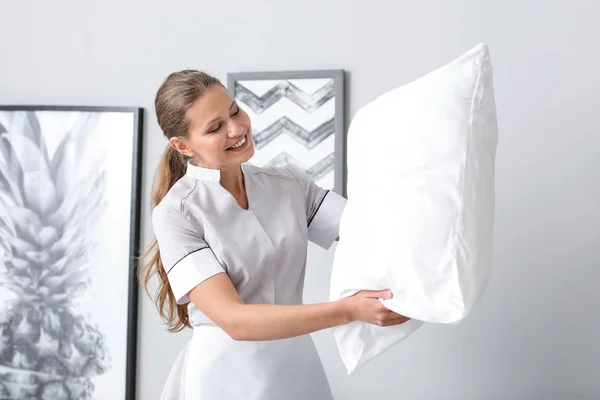Beautiful female housekeeper with soft pillow in room — Stock Photo, Image