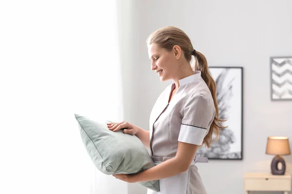 Beautiful female housekeeper with soft pillow in room — Stock Photo, Image