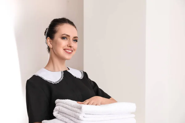 Vacker kvinnlig hushållerska med rena handdukar i rum — Stockfoto