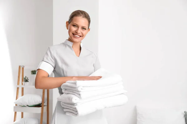Prachtige vrouwelijke huishoudster met schone handdoeken in kamer — Stockfoto