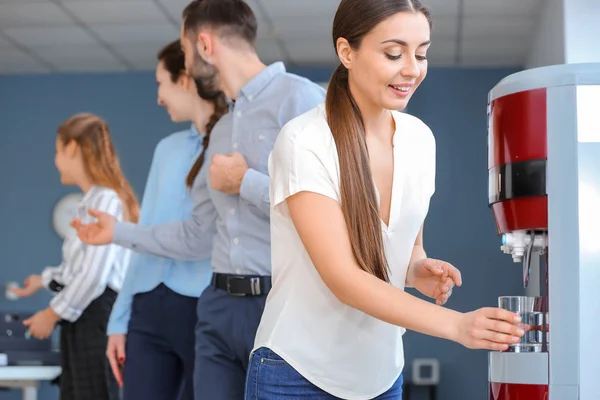 Colleagues drinking water from cooler in office — Stock Photo, Image