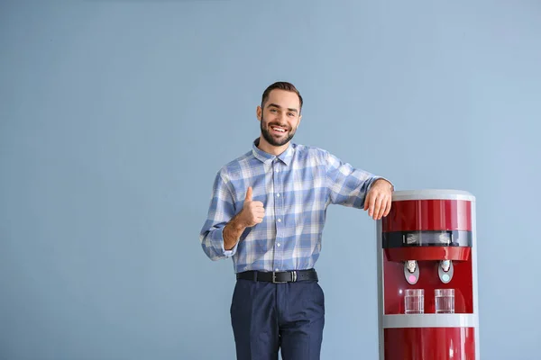 Hombre cerca de enfriador de agua contra fondo de color — Foto de Stock