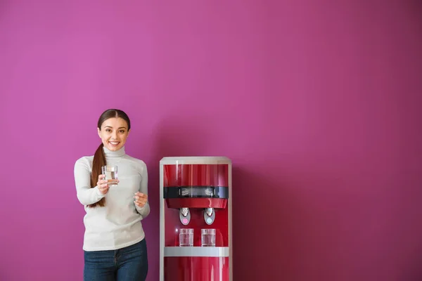 Mulher perto do refrigerador de água contra fundo de cor — Fotografia de Stock