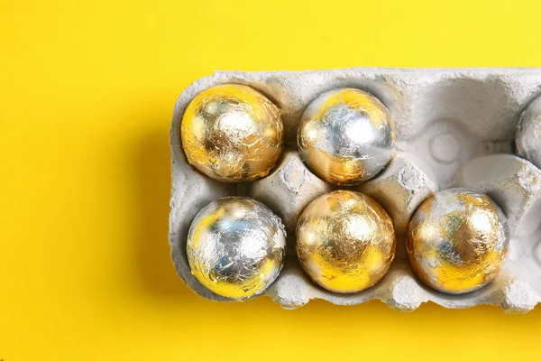 Porta cartone con uova di Pasqua su sfondo a colori — Foto Stock