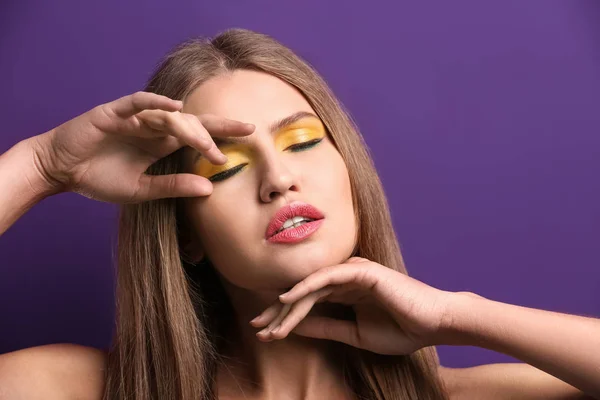 Mooie jonge vrouw met lichte make-up op kleur achtergrond — Stockfoto