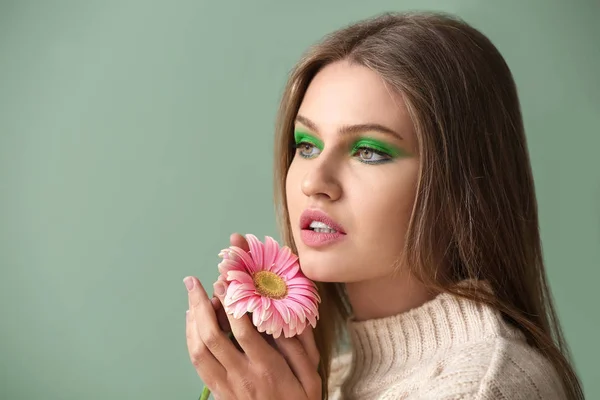 Mulher bonita com maquiagem brilhante e flor no fundo de cor — Fotografia de Stock