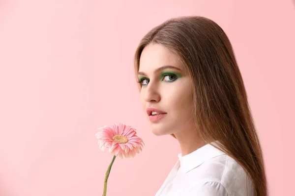 明るいメイクや背景の色の花を持つ美しい若い女性 — ストック写真