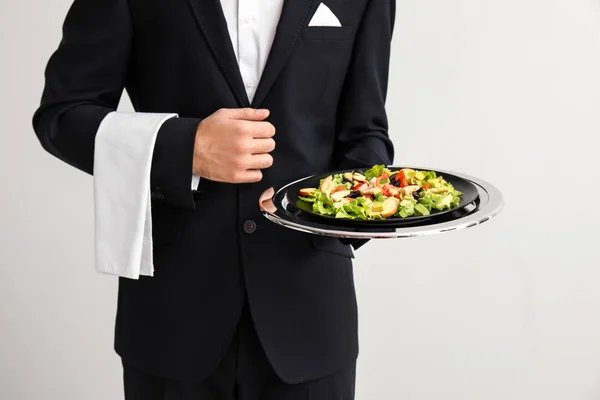 Číšník s čerstvým salátem na světlé pozadí — Stock fotografie