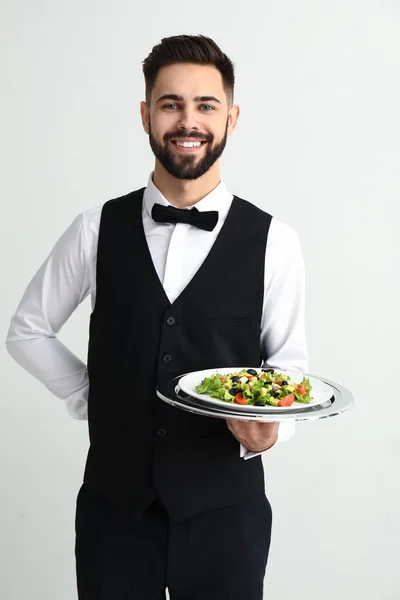 Waiter with tasty salad on light background — Stock Photo, Image