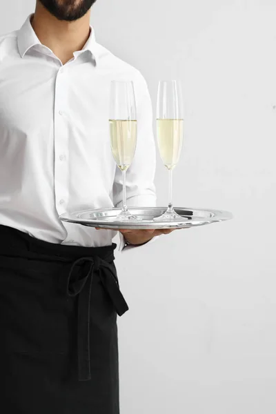 Pohledný číšník s brýlemi šampaňského na světlé pozadí — Stock fotografie