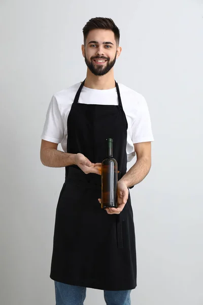 Camarero guapo con botella de vino sobre fondo claro —  Fotos de Stock