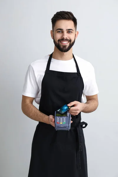 Handsome waiter with payment terminal on light background — Stock Photo, Image