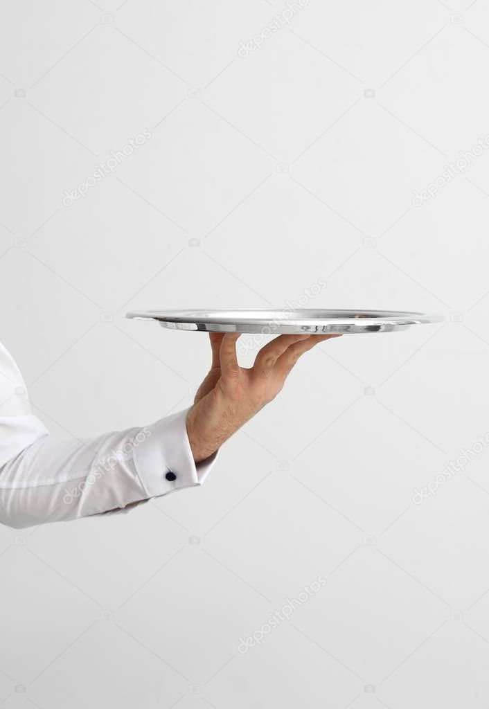 Hand of waiter with empty tray on light background