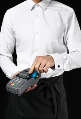 Ödeme koyu arka plan üzerinde terminal ile yakışıklı garson