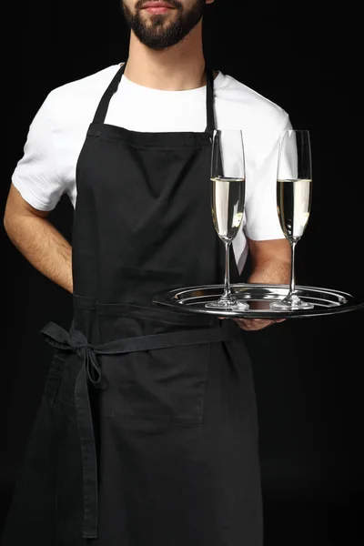 Красивый официант с бокалами шампанского на тёмном фоне — стоковое фото