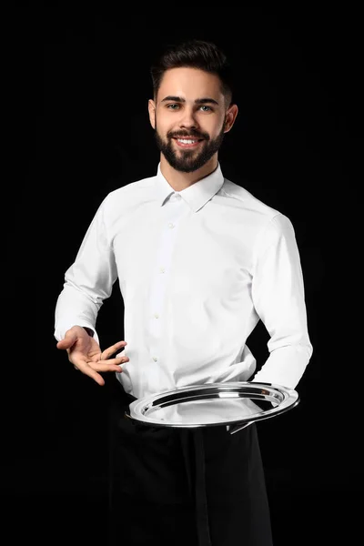 Handsome waiter with empty tray on dark background — Stock Photo, Image