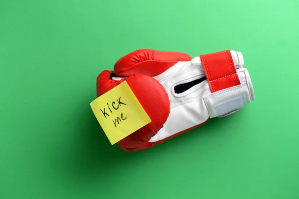 Guante de boxeo y nota adhesiva con texto KICK ME sobre fondo de color. Broma del Día de los Inocentes — Foto de Stock