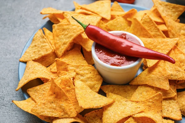 Plato con sabrosos nachos y salsa de tomate en la mesa — Foto de Stock