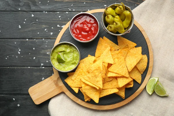 Tablero con sabrosos nachos y salsas en la mesa — Foto de Stock