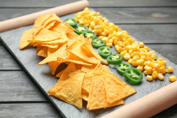 Stojan s chutné nachos, jalapeno a kukuřice na stole — Stock fotografie