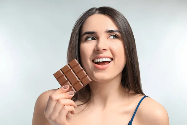 Mulher bonita com chocolate saboroso no fundo claro — Fotografia de Stock