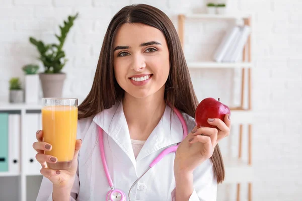 Portret van vrouwelijke voedingsdeskundige met glas sap en apple in haar kantoor — Stockfoto