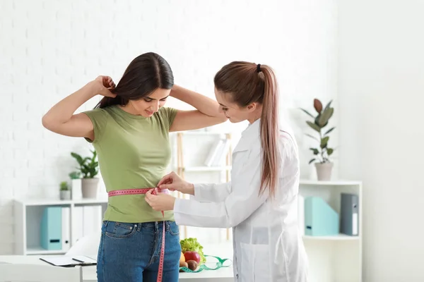 Nutricionista midiendo cintura de mujer joven en clínica de pérdida de peso —  Fotos de Stock
