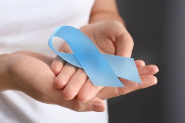 Mavi kurdele gri arka plan üzerinde closeup tutan kadın. Kanser farkındalık kavramı