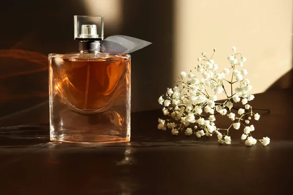 Frasco transparente de perfume con hermosas flores en la mesa oscura —  Fotos de Stock