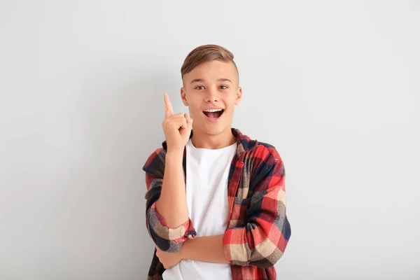 Emotionaler Teenager mit erhobenem Zeigefinger auf weißem Hintergrund — Stockfoto