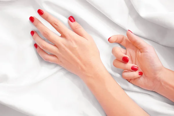 Female hands with stylish beautiful manicure on white fabric — Stock Photo, Image