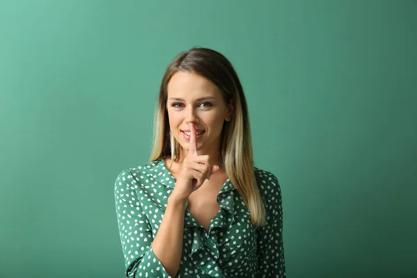 Schöne junge Frau zeigt Geste der Stille auf farbigem Hintergrund — Stockfoto